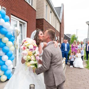 Bruidspaar Pim en Gladys kussen elkaar bij hun huis in Arnhem, bruidsreportage door Arthur van Leeuwen.