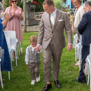 Bruidegom Pim loopt hand in hand met een zijn zoon, de ringdrager, naar de bruiloftsceremonie in Ewijk