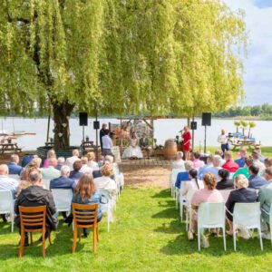 Bruidsceremonie aan het water bij Paviljoen het Buitenhuis, Ewijk, met het bruidspaar Pim en Gladys onder een grote boom.