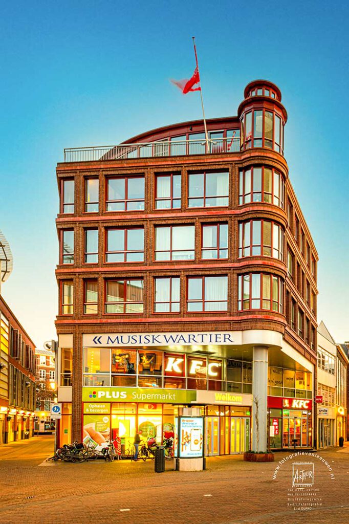 avondopname van het Musiskwartier, een rood bakstenen gebouw met winkels in Arnhem.