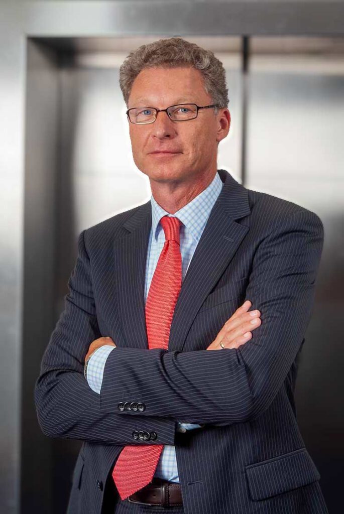 Zakelijk portret van een man met bril en gevouwen armen in een donker krijtstreep pak met rode das.